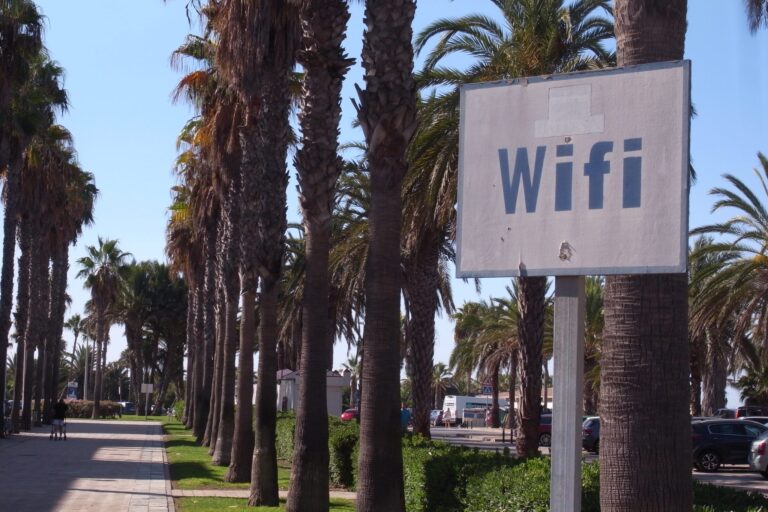 Old WiFi sign by a palm-lined boulevard